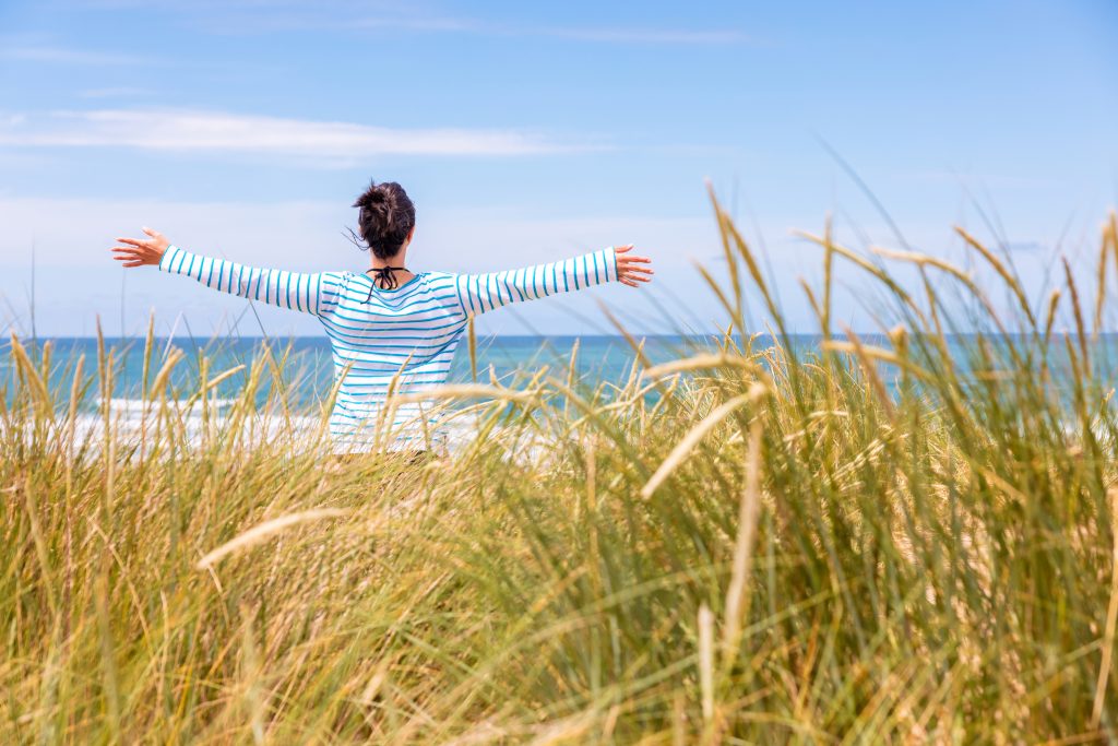 woman in dune grass with arms outstretched